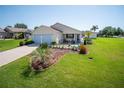 Inviting home featuring a well-kept lawn, mature landscaping, and an attached garage, promising suburban charm at 2167 Kerwood Loop, The Villages, FL 32162