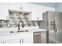 Bright kitchen boasts stainless steel appliances, modern white cabinets, and stylish backsplash, offering a sleek design at 228 Ring Rd, Orlando, FL 32811