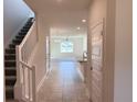View of the neutral-toned entryway featuring a staircase and ceramic tile floors with open kitchen view at 4433 Sagefield Dr, St Cloud, FL 34773