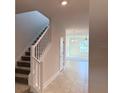 View of the neutral-toned entryway featuring a staircase and ceramic tile floors at 4433 Sagefield Dr, St Cloud, FL 34773