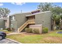 A close exterior view of the condos featuring green facade, wooden staircase and lush green grass at 5071 Eaglesmere Dr # C01, Orlando, FL 32819