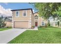 Two-story home featuring neutral siding, manicured lawn, mature trees and an attached two-car garage at 510 Lobelia Dr, Davenport, FL 33837