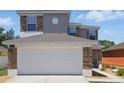 Two-story home featuring a large white garage door and decorative stone accents at 5107 Ne 122Nd Blvd, Oxford, FL 34484
