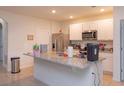 Well-lit kitchen featuring a granite-topped island, stainless-steel refrigerator, and white cabinetry at 5367 Douglas Fir Dr, St Cloud, FL 34771