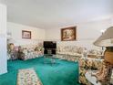 Cozy living room with floral patterned furniture, green carpet, and glass coffee table at 744 Wyman Ct # 744, Orlando, FL 32809