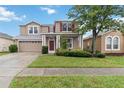 Charming two-story home featuring a red front door, attached garage, and well-maintained landscaping at 7551 Bear Claw Run, Orlando, FL 32825