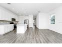 Open floor plan featuring kitchen with white cabinets, stainless appliances, and wood-look flooring at 809 Benoi Dr, Davenport, FL 33896