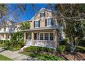 Inviting two-story home boasts a charming front porch, black shutters, and well-maintained landscaping at 9141 Camden Gardens St, Orlando, FL 32827