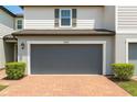 Attached two-car garage with a gray door and a brick driveway with landscape at 1045 Desert Candle Dr, Ocoee, FL 34761