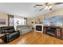 Inviting living room with a fireplace, ceiling fan, and large TV at 13009 Plum Lake Cir, Minneola, FL 34715
