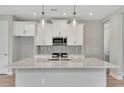 Modern kitchen features a gray backsplash, stainless appliances, and a large center island with sink at 1459 Santorini Way, Tavares, FL 32778