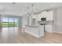 Bright, open-concept kitchen features white cabinets, a center island, and sliding glass doors leading to backyard at 1459 Santorini Way, Tavares, FL 32778
