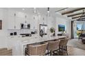 Open-concept kitchen with an island, white cabinets, stainless steel appliances, and a view into the living area at 1459 Santorini Way, Tavares, FL 32778