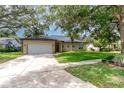 Inviting single-story home featuring a spacious driveway, two-car garage, and lush green lawn with mature trees at 196 Morning Glory Dr, Lake Mary, FL 32746