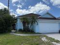 Charming light blue home featuring a white garage door and complemented by palm trees in the front yard at 307 Hollingshead Loop, Davenport, FL 33896