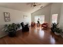A living room with hardwood floors, a ceiling fan, three windows, and three chairs at 307 Hollingshead Loop, Davenport, FL 33896