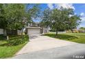 View of the home with a long driveway and large trees in the front yard at 401 Magpie Ct, Kissimmee, FL 34759