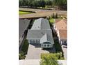 Birds eye view of a charming gray home with a dark roof, manicured lawn and brick driveway at 406 Alcove Dr, Groveland, FL 34736