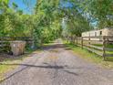 Gravel driveway leading to property with a wooden fence, trees, and an ADT security sign at 4432 Freedom Rd, Kissimmee, FL 34746