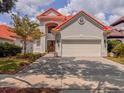 Charming two-story home featuring a red tile roof, a brick driveway and lush landscaping at 8515 Saint Marino Blvd, Orlando, FL 32836