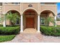 Charming front entrance with arched columns, a decorative wood door, and manicured landscaping at 1010 Terrace Blvd, Orlando, FL 32803
