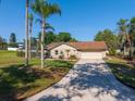 Charming single-story home with a manicured lawn, palm trees and paved driveway on a sunny day at 10545 Parkway Dr, Clermont, FL 34711