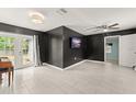 Modern living room with sleek tile floors, a ceiling fan, and glass doors to the backyard at 16 Lake Drive, Debary, FL 32713