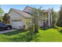 View of a two-story home with an attached garage and landscaped yard at 16249 Se 162Nd Ct, Weirsdale, FL 32195