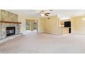 Open-concept living area with a stone fireplace, neutral carpeting, and a view into the kitchen at 20330 Majestic St, Orlando, FL 32833