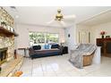 Cozy living room featuring a stone fireplace, ceiling fan, and tile floors for easy maintenance at 8625 Shady Glen Dr, Orlando, FL 32819