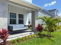 Inviting front porch with a cushioned porch swing, palm trees and colorful foliage that creates a relaxing ambiance at 10183 Peebles St, Orlando, FL 32827