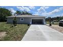 Exterior shot showing concrete driveway and open garage of newly built single-story home under cloudy blue skies at 141 W G H Washington St, Apopka, FL 32703