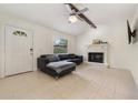 Cozy living room with tiled floors, fireplace, ceiling fan, and a comfortable black leather couch at 2040 E Triangle Dr, Longwood, FL 32779