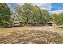 Large lot featuring a single-story home, RV, and outbuildings under a canopy of mature trees at 24089 Ne 152Nd Ln, Fort Mc Coy, FL 32134