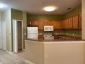 Cozy kitchen featuring wooden cabinets, white appliances, and a breakfast bar at 6169 Metrowest Blvd # 102, Orlando, FL 32835