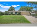 Charming single-story home with lush landscaping, brick accents, and a paver driveway at 7549 Lake Marsha Dr, Orlando, FL 32819