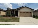 Beige single-story home featuring an attached two-car garage, manicured lawn, and carefully placed landscaping at 8933 Hinsdale Heights Dr, Polk City, FL 33868