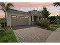 Charming single-story home with a brick driveway, lush landscaping, and a welcoming covered entrance at sunset at 10203 Henbury St, Orlando, FL 32832