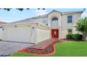 Two-story home with a two car garage, tile walkway, and bright red front door at 11257 Dacre Ln, Orlando, FL 32824