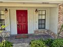 A bright red front door with sidelights and sconce lighting creates a charming entryway to the home at 1219 Serissa Ct, Orlando, FL 32818