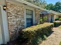 A close up of the side of the home showing brick siding, trimmed hedges, and a sidewalk at 1219 Serissa Ct, Orlando, FL 32818