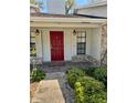 Inviting front entrance with a vibrant red door, stylish sconces, and neatly manicured shrubs enhancing curb appeal at 1219 Serissa Ct, Orlando, FL 32818