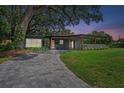 An exterior view of a gray home with a paver driveway, manicured lawn, and a covered entrance at 1401 Canberra Ave, Orlando, FL 32806