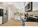 Well-lit kitchen featuring granite countertops, stainless steel appliances, and wood-look flooring at 1800 Silver Valley Ct, Apopka, FL 32712