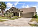 Charming single Gathering home with a well-manicured lawn, mature palm trees, and a two-car garage at 259 Blue Cypress Dr, Groveland, FL 34736