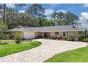 Charming ranch-style home with brick circular drive, lush lawn, mature trees and stone accents at 303 S Sweetwater Blvd, Longwood, FL 32779