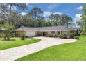 Charming ranch-style home with brick circular drive, lush lawn, mature trees and stone accents at 303 S Sweetwater Blvd, Longwood, FL 32779