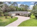 Charming ranch-style home with brick circular drive, lush lawn, mature trees and stone accents at 303 S Sweetwater Blvd, Longwood, FL 32779