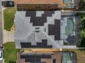 Aerial view of a home's solar panels and screened-in pool, situated amongst neighboring properties at 325 Aldridge Ln, Davenport, FL 33897
