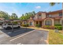 Townhome featuring assigned parking, mature landscaping, and classic stucco exterior under blue sky at 424 Club Dr, Winter Springs, FL 32708